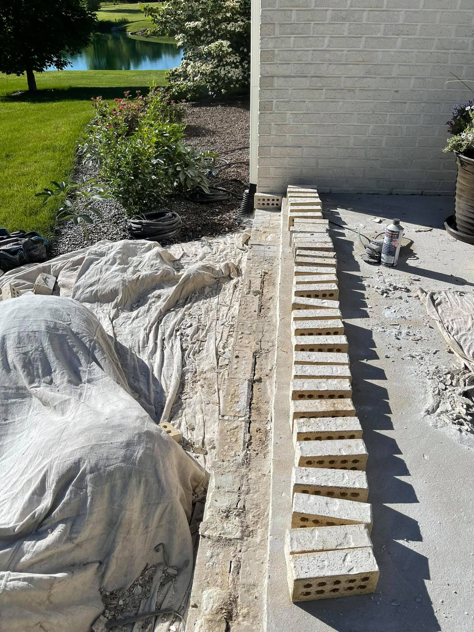 A row of bricks are sitting on the ground in front of a white brick wall.