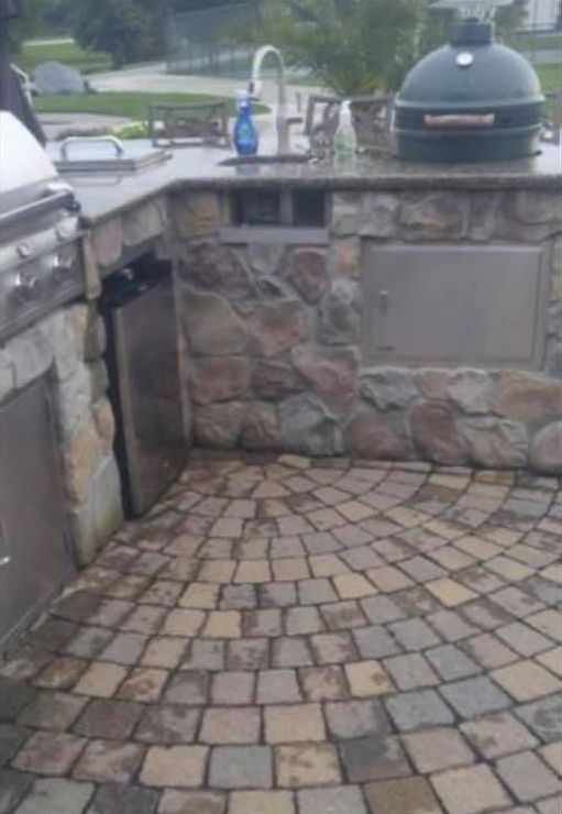 A kitchen with a grill and a sink on a brick floor.