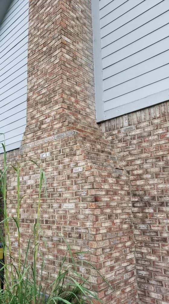 A brick wall with a chimney on the side of a house.