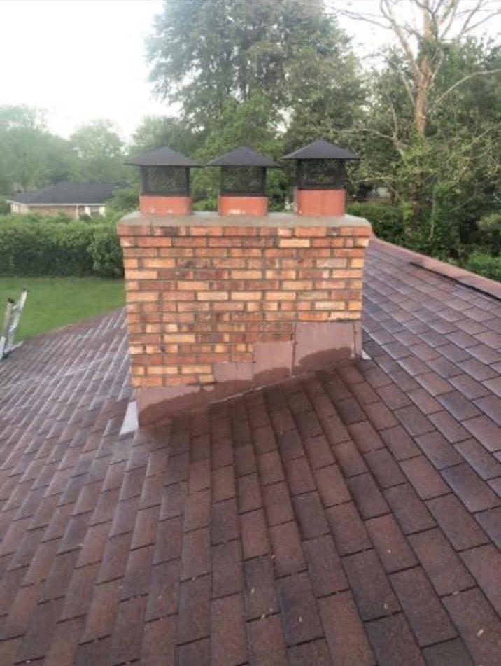 A brick chimney is sitting on top of a brick roof.