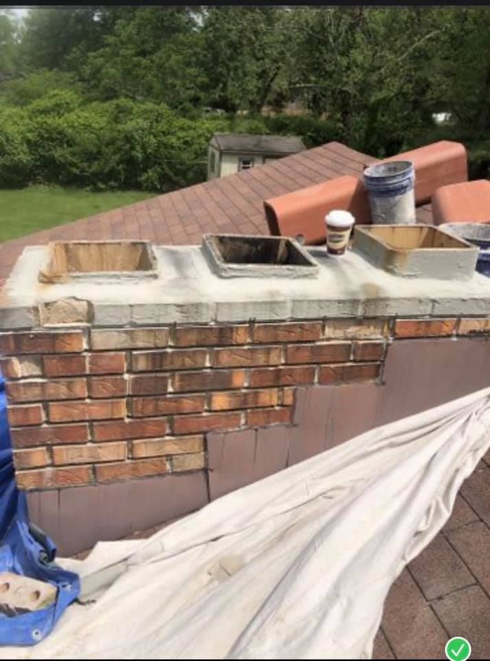 A brick chimney is being painted on the roof of a house.