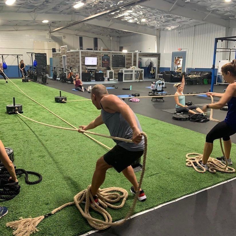 A man and a woman are pulling ropes in a gym.