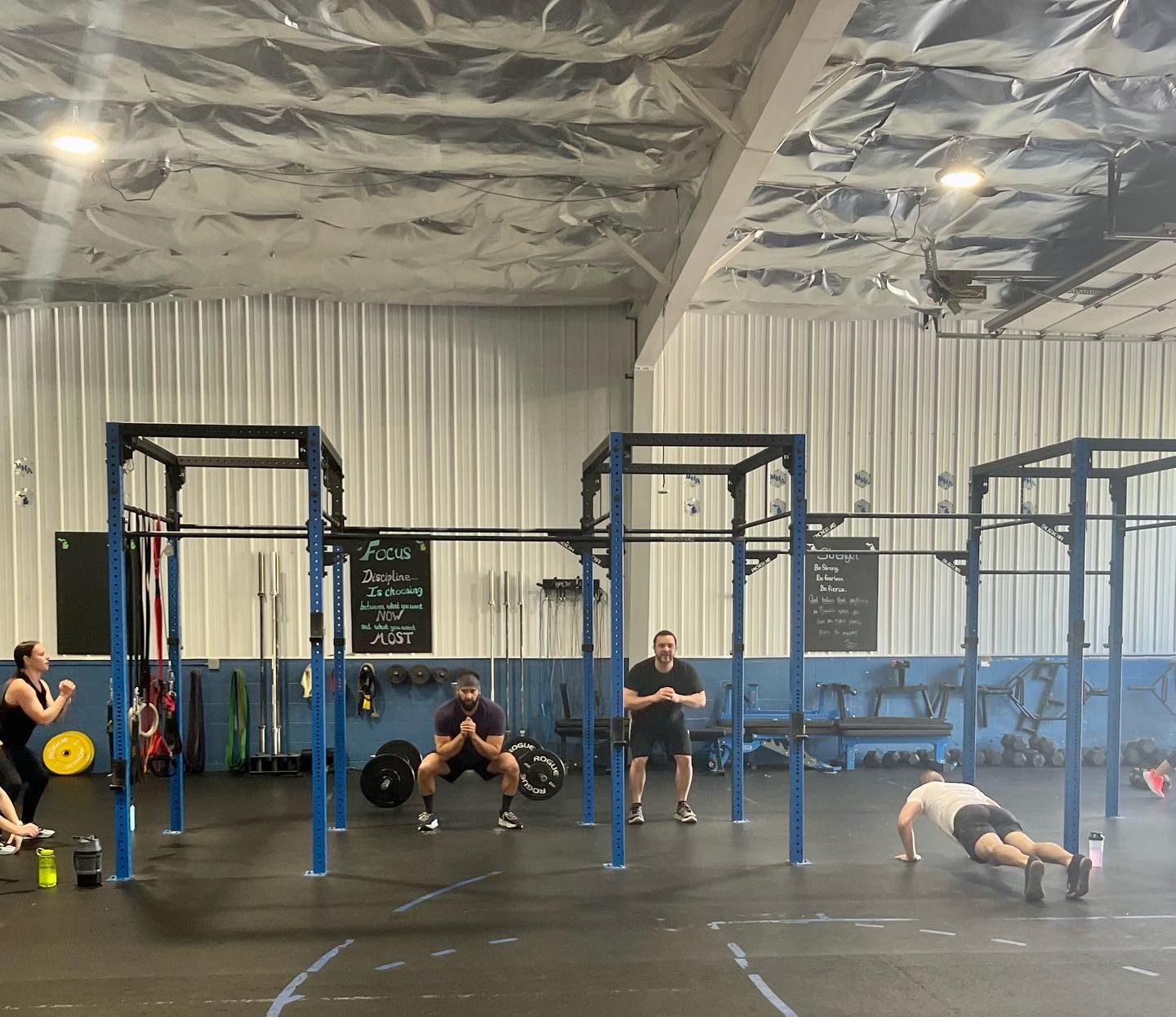 A group of people are doing push ups in a gym.