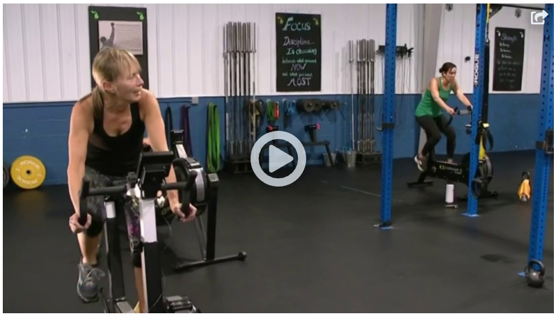 A woman is riding an exercise bike in a gym