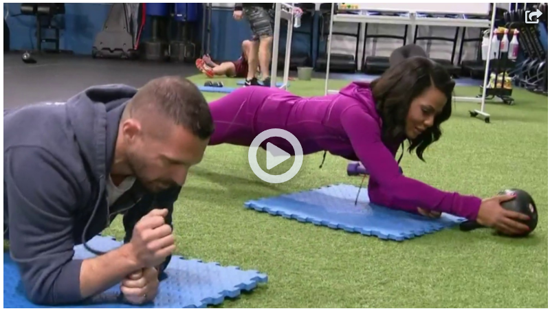 A man and a woman are doing plank exercises in a gym.