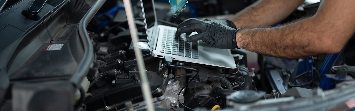 A mechanic with black gloves working on a car engine, replacing a filter.