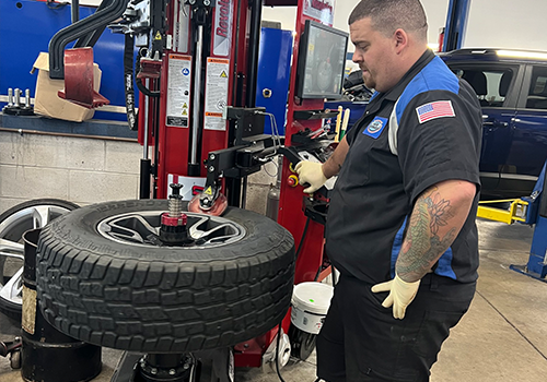 A man is changing a tire on a machine in a garage.