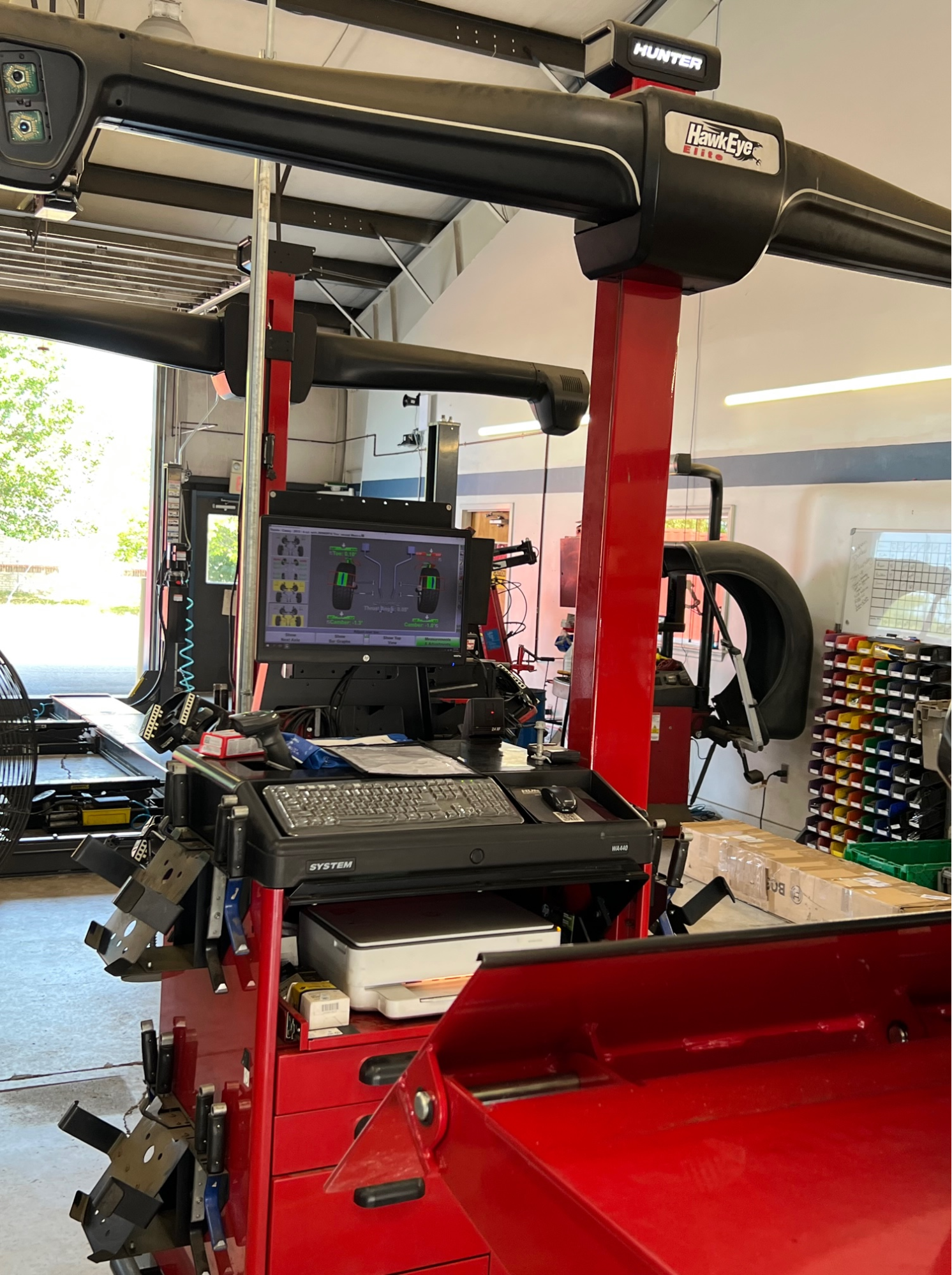 A red machine with a computer on top of it in a garage.