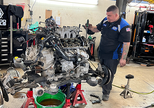 A man is working on a car engine in a garage.