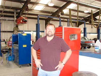 A man standing in a garage with his hands on his hips