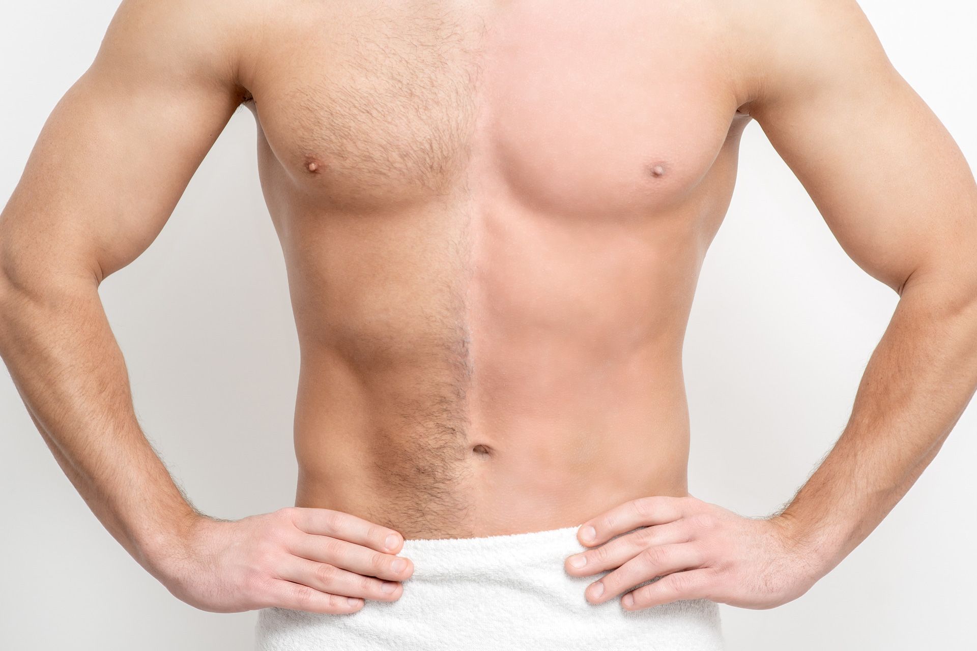 A man without a shirt is standing with his hands on his hips.