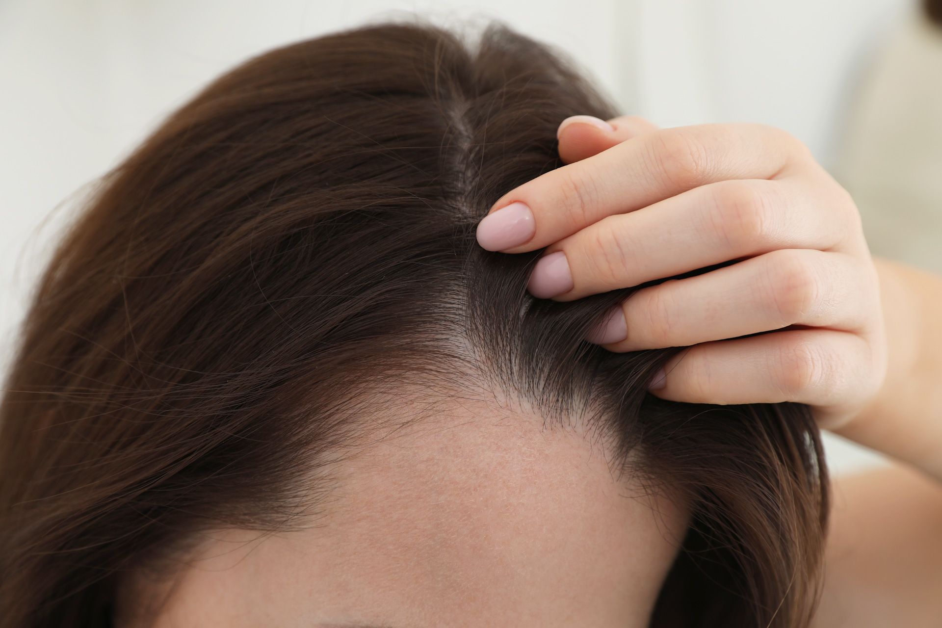 A woman is touching her hair with her hand.