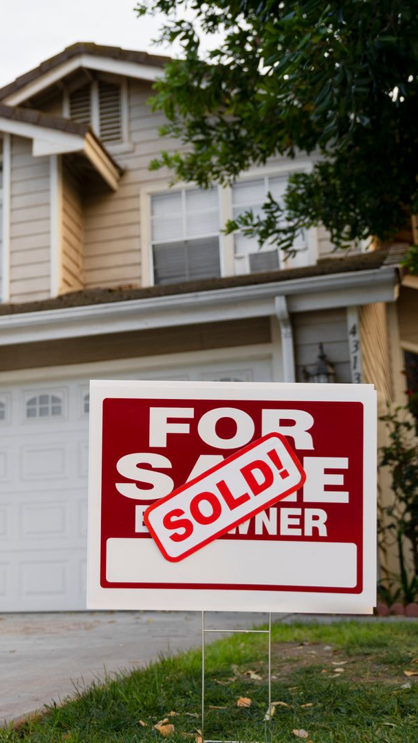 Living room with light gray walls, white sofa, rug, and black accent furniture, near a window.