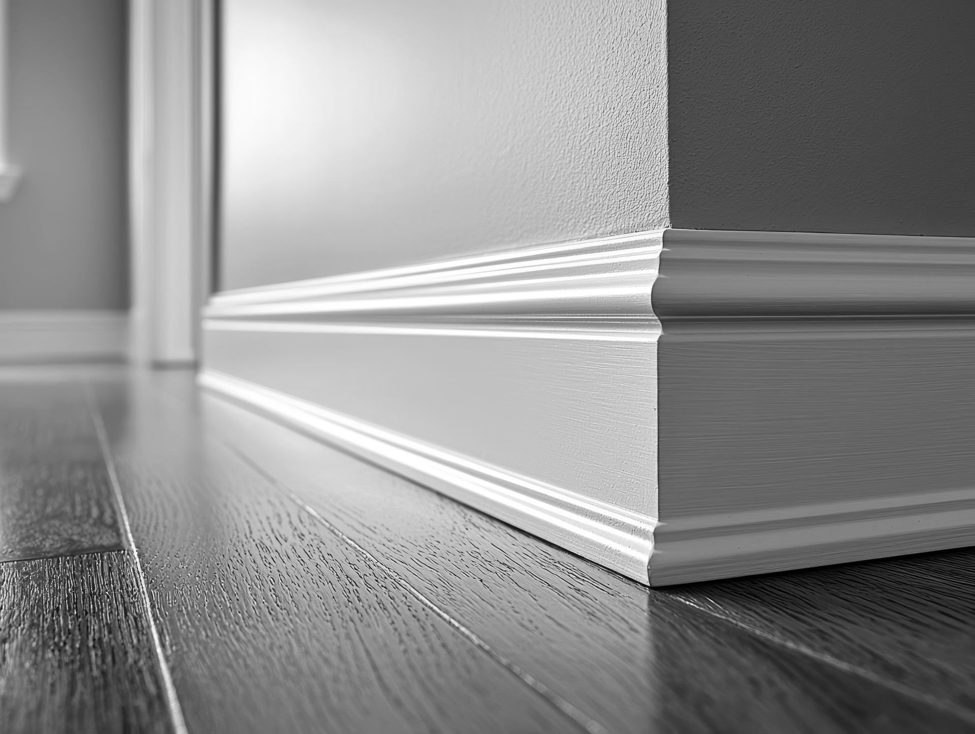 Une photo en noir et blanc d'une moulure blanche sur un plancher en bois.