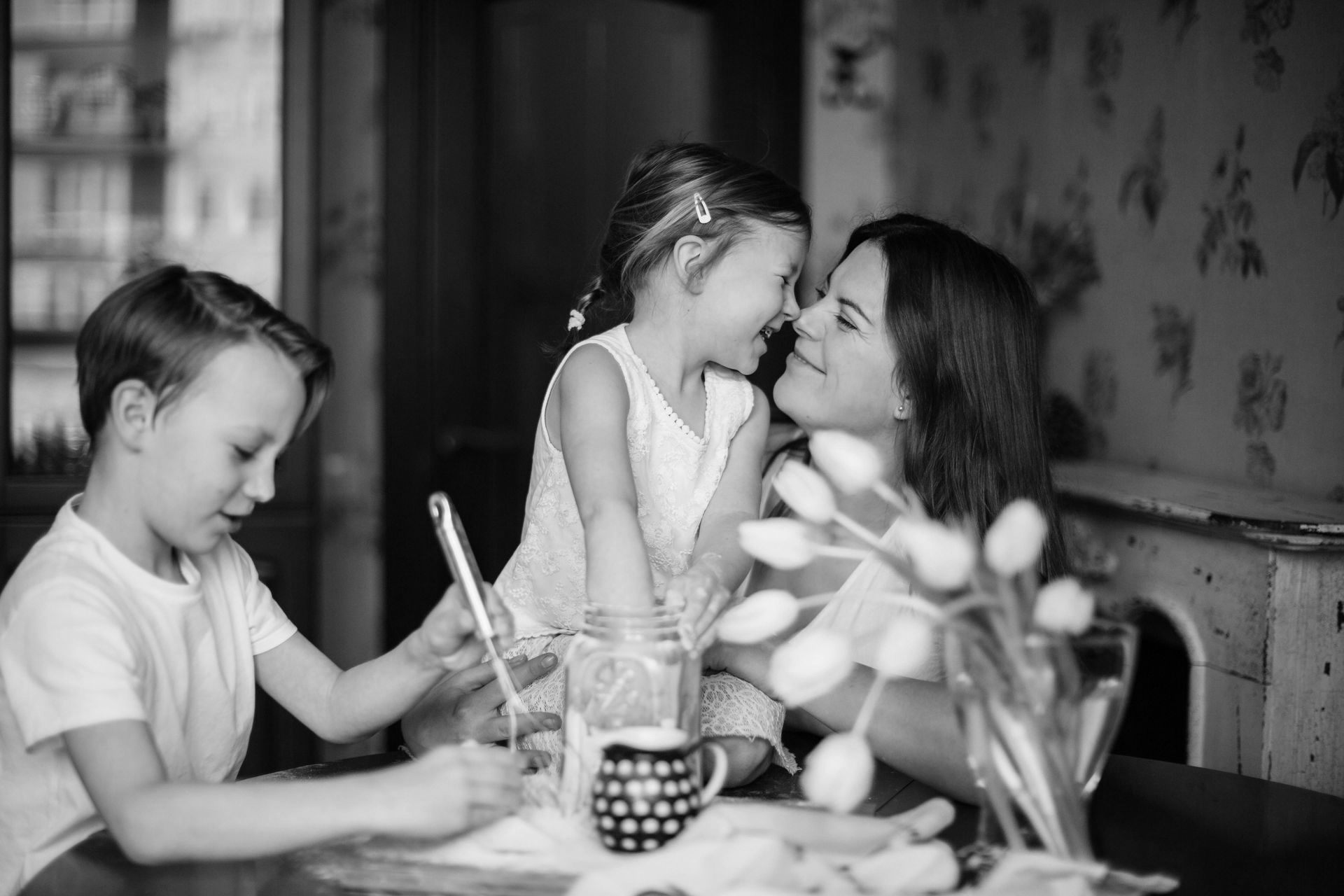 Une femme est assise à une table avec deux enfants.