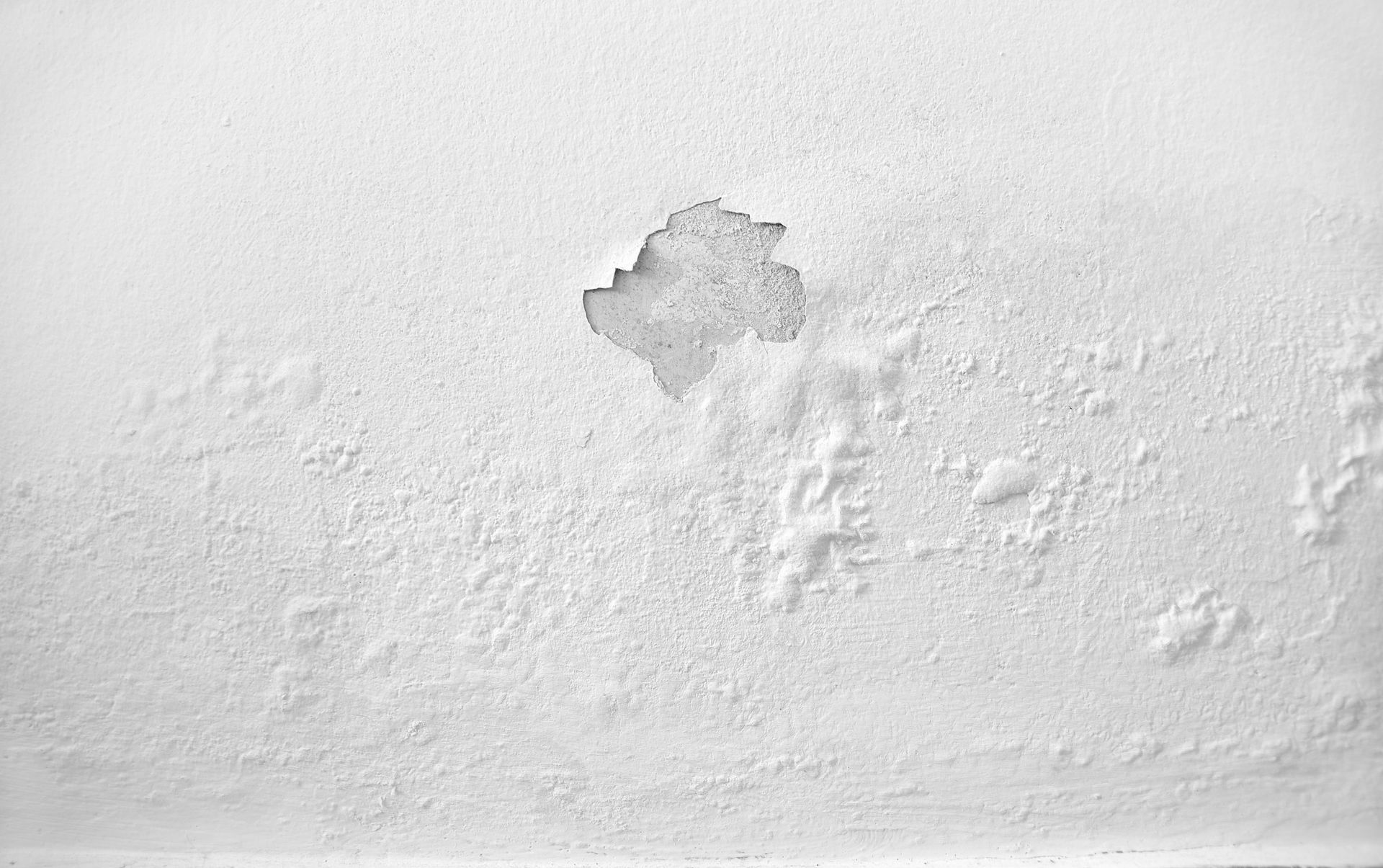 Un gros plan d'un mur blanc avec un trou dedans.