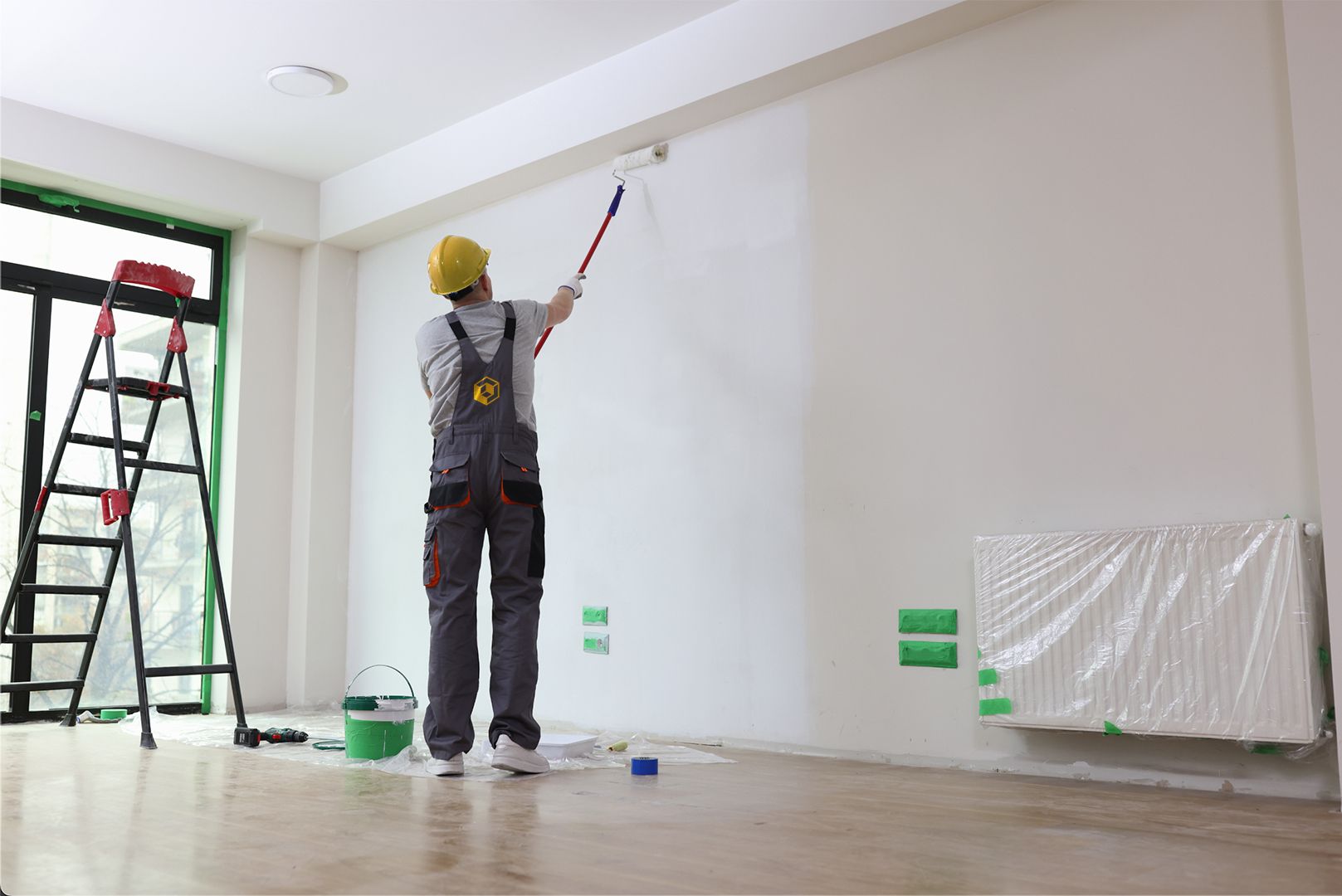 a man is painting a wall with a roller in an empty room .