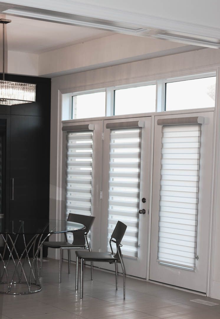 a dining room with a table and chairs and blinds on the windows .