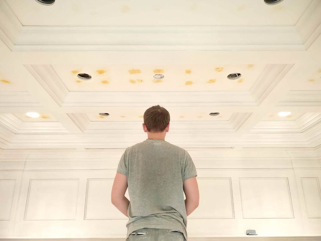 a man is standing in a room looking up at the ceiling .