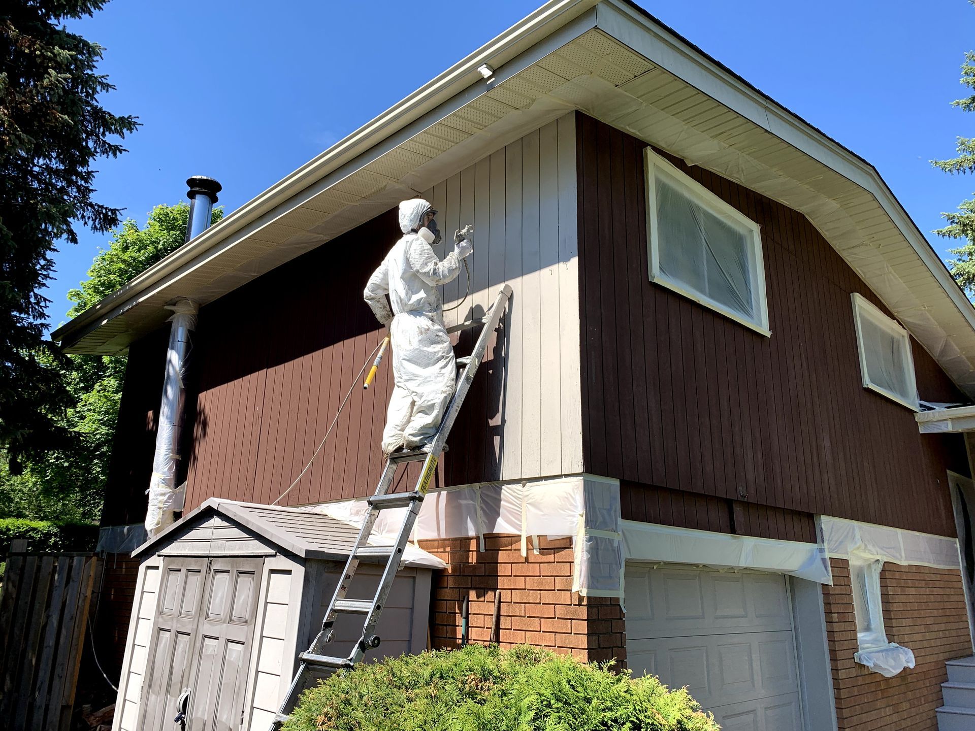 a man on a ladder is painting the side of a house .