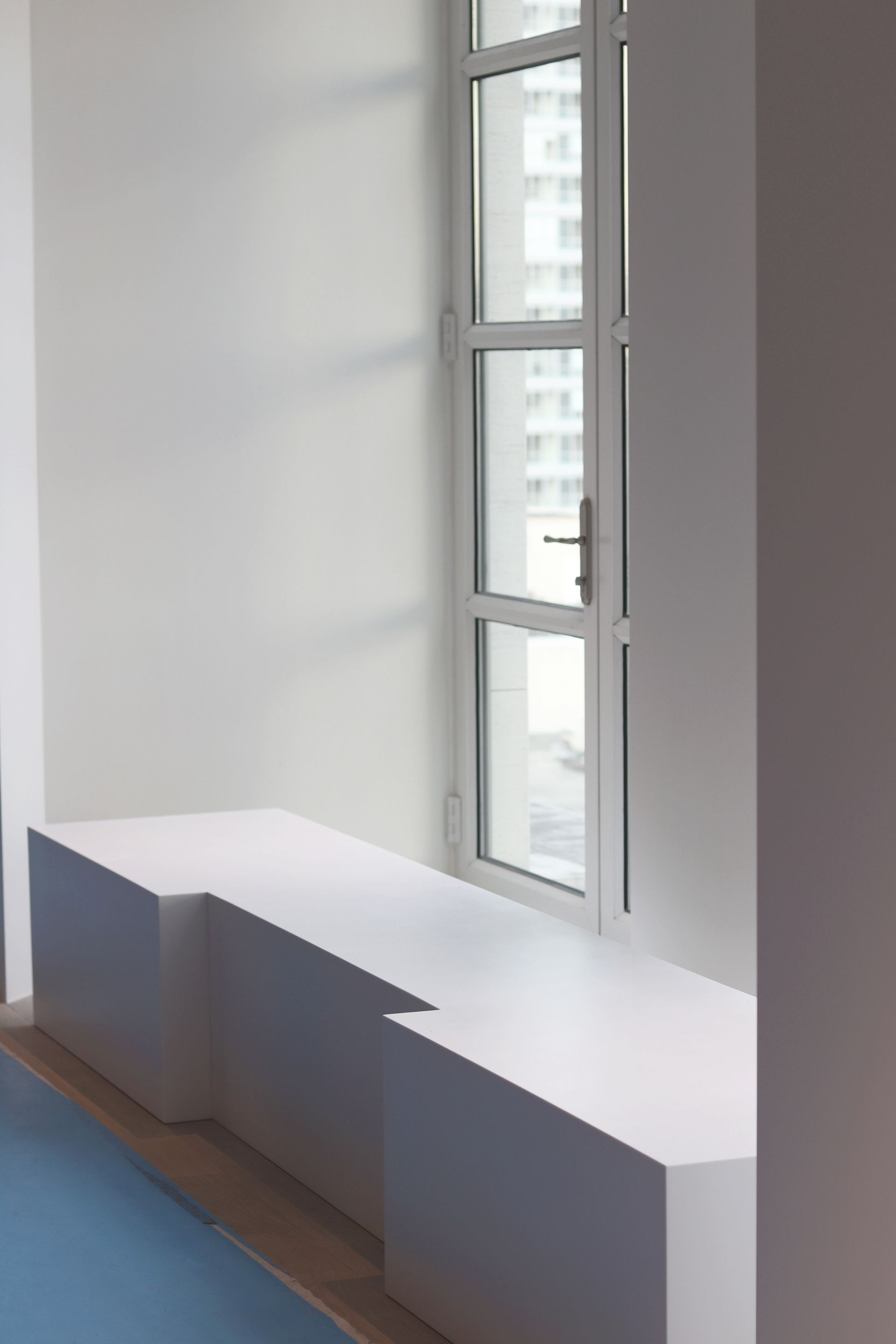 a white bench is sitting next to a window in a room .