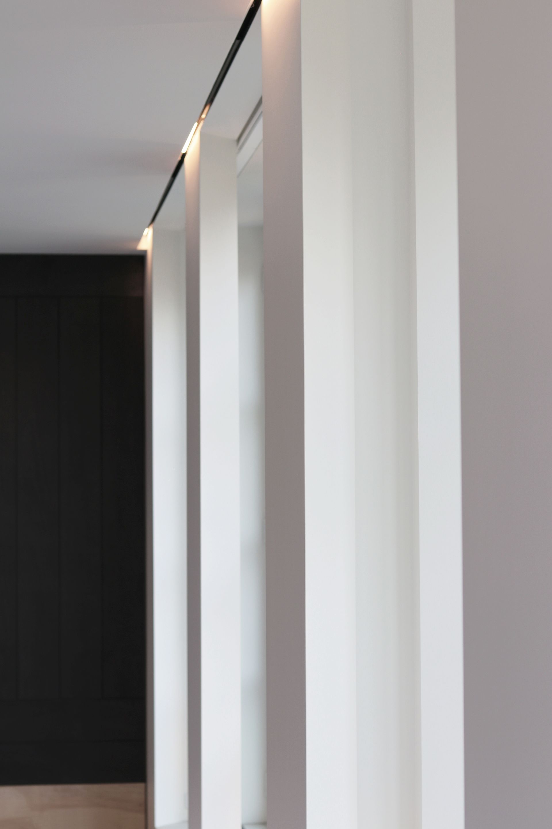 a long hallway with white columns and a black wall