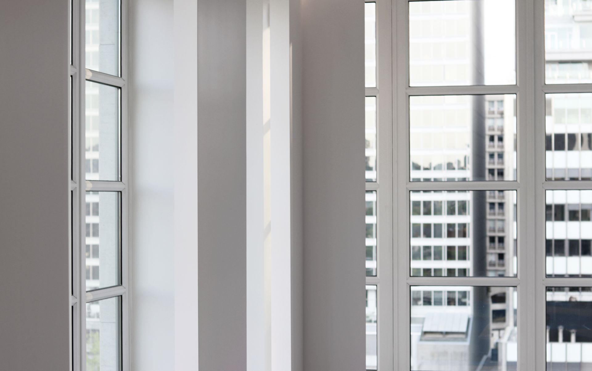 an empty room with a lot of windows and a view of a city .