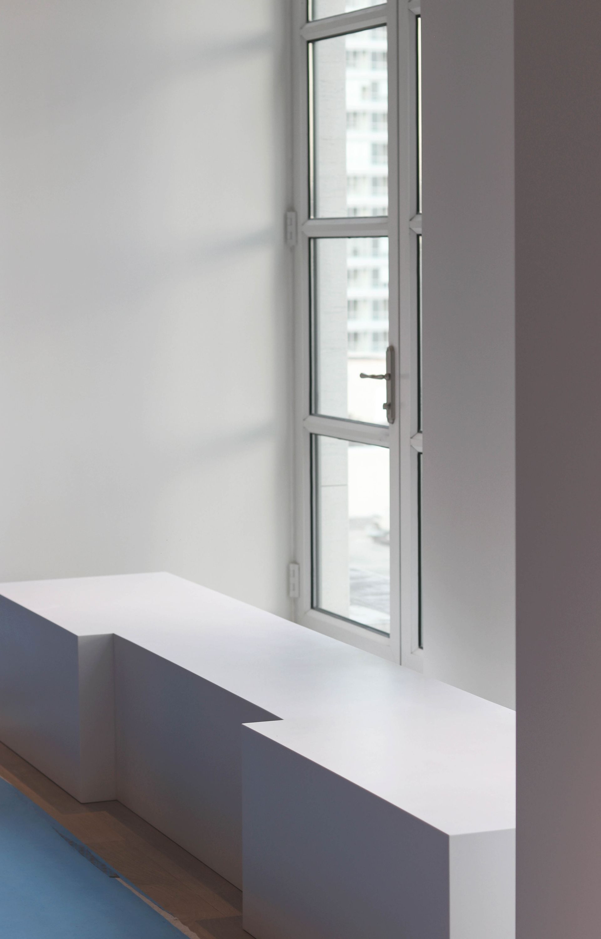 a white bench is sitting next to a window in a room .