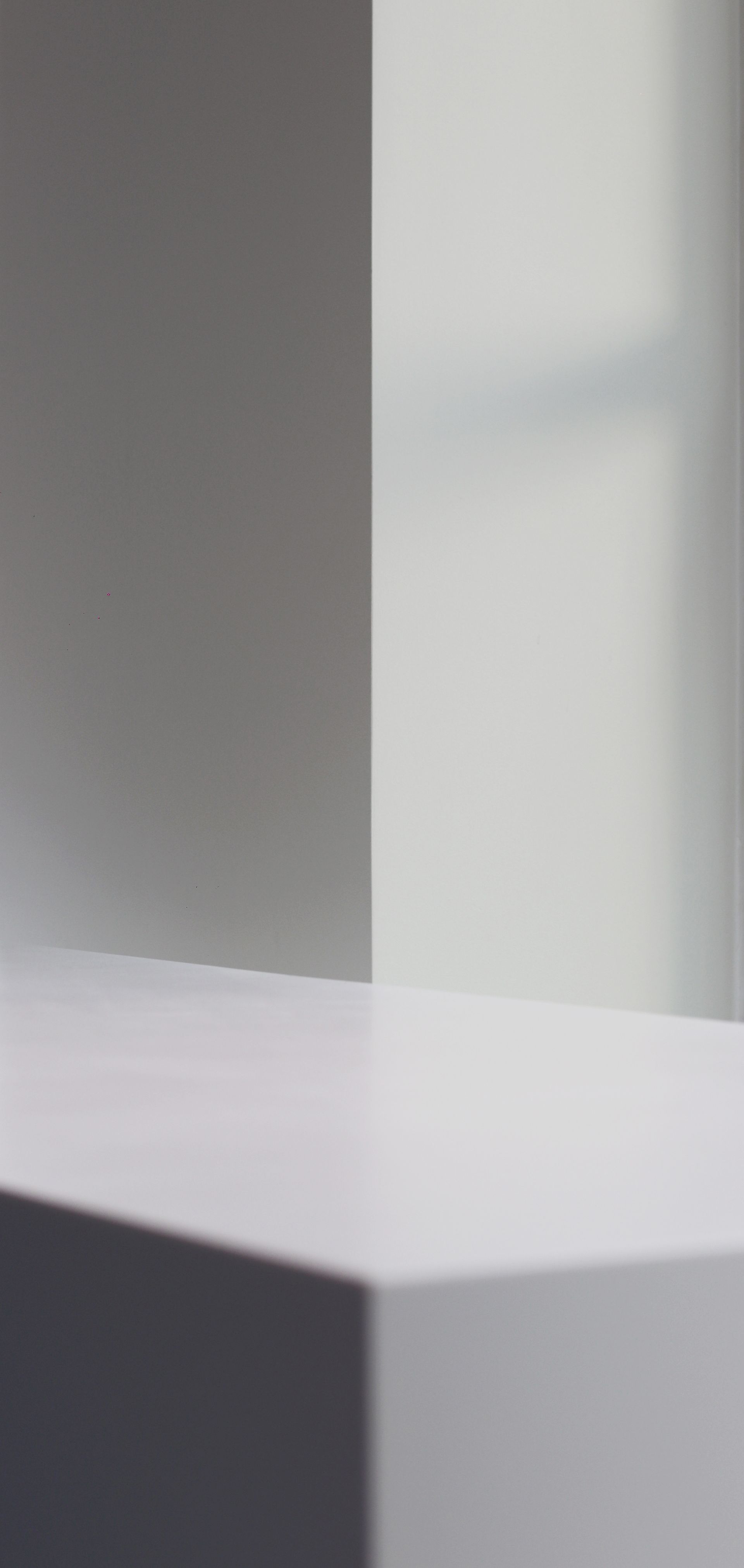 a white table with a gray corner and a window in the background .