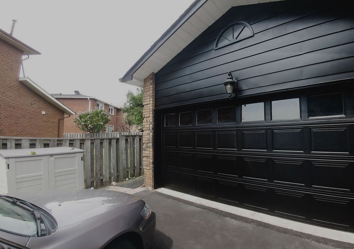 a car is parked in front of a black garage door