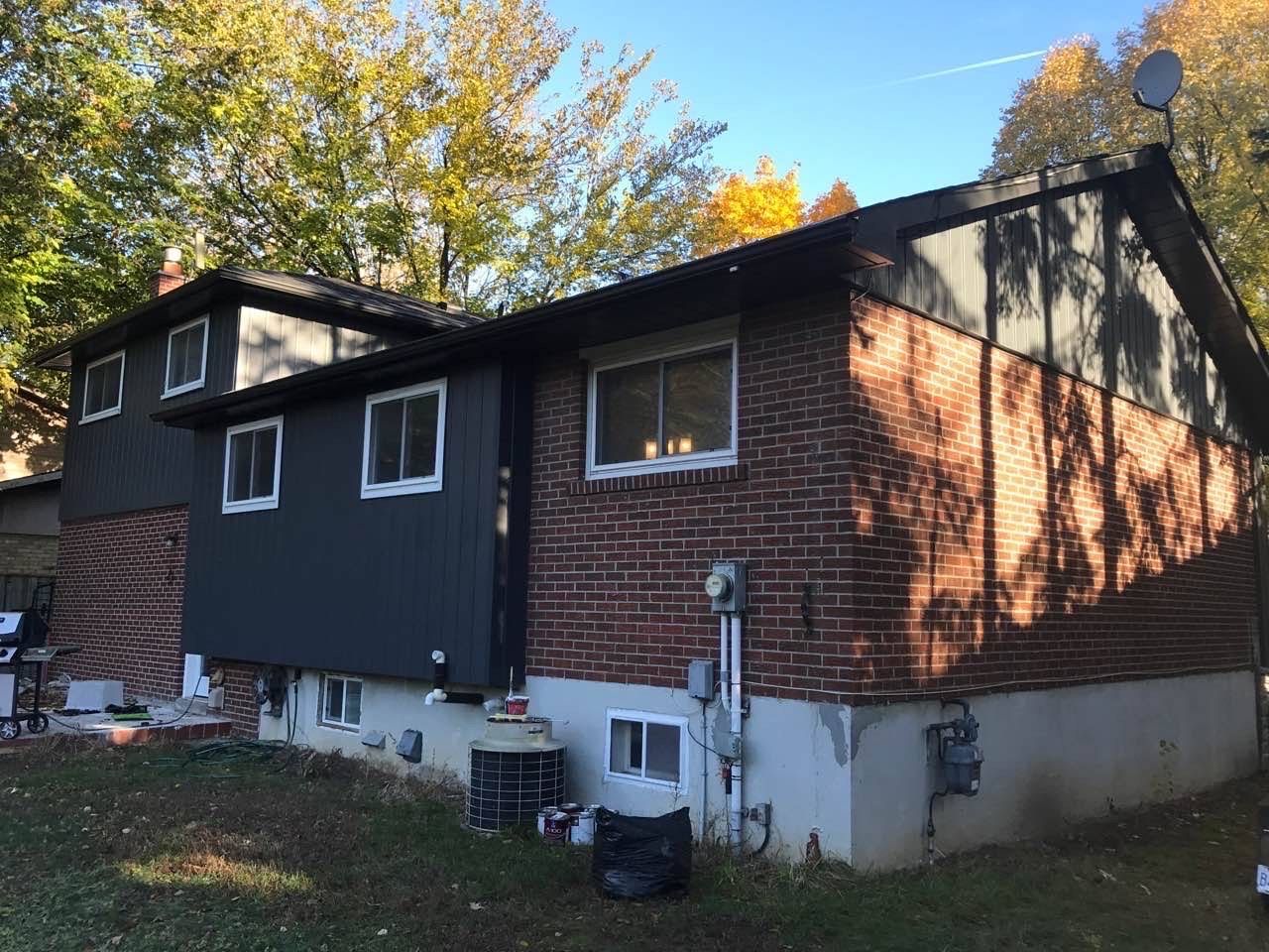 a brick house with a black siding and a satellite dish on the roof .