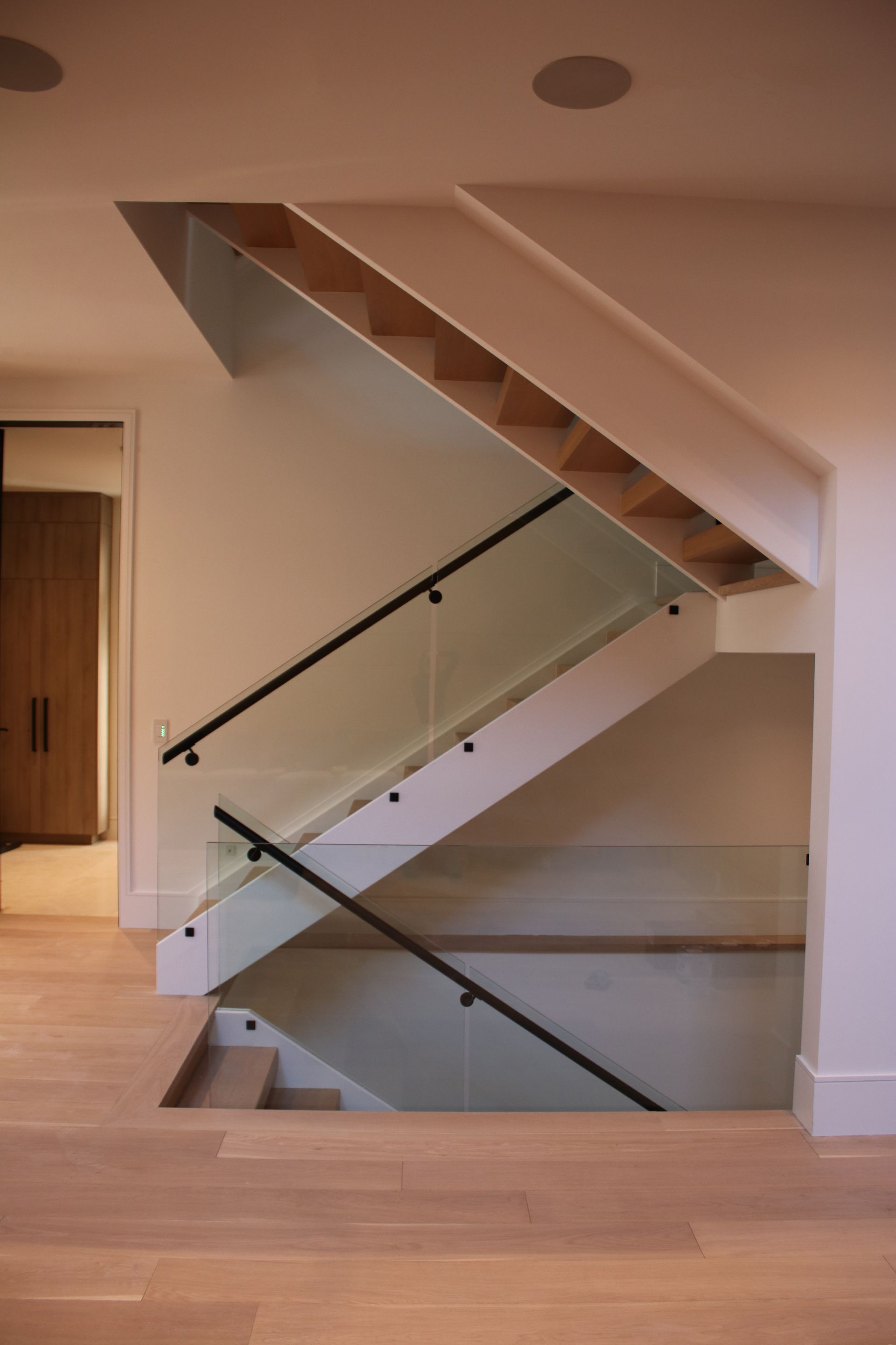 a staircase with a glass railing and wooden steps in an empty room .