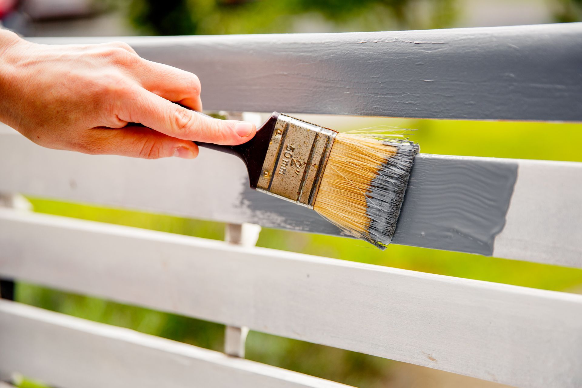 a person is painting a white fence with a brush .