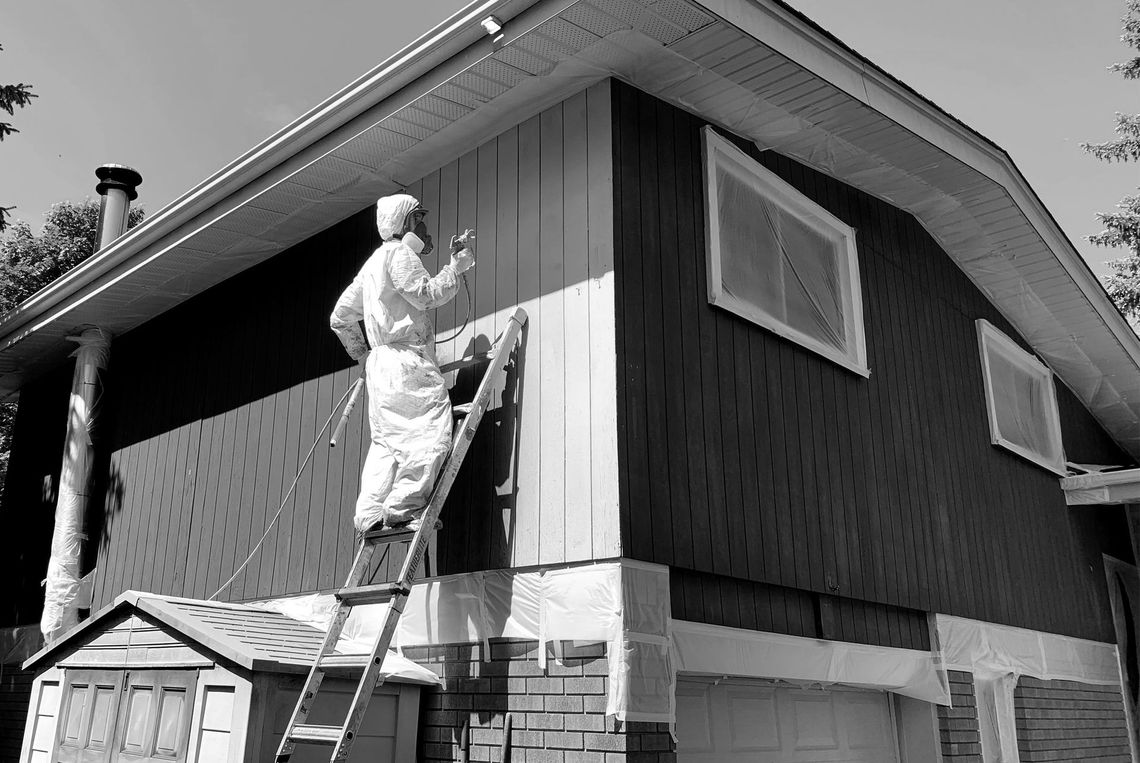 a man on a ladder is painting the side of a house .