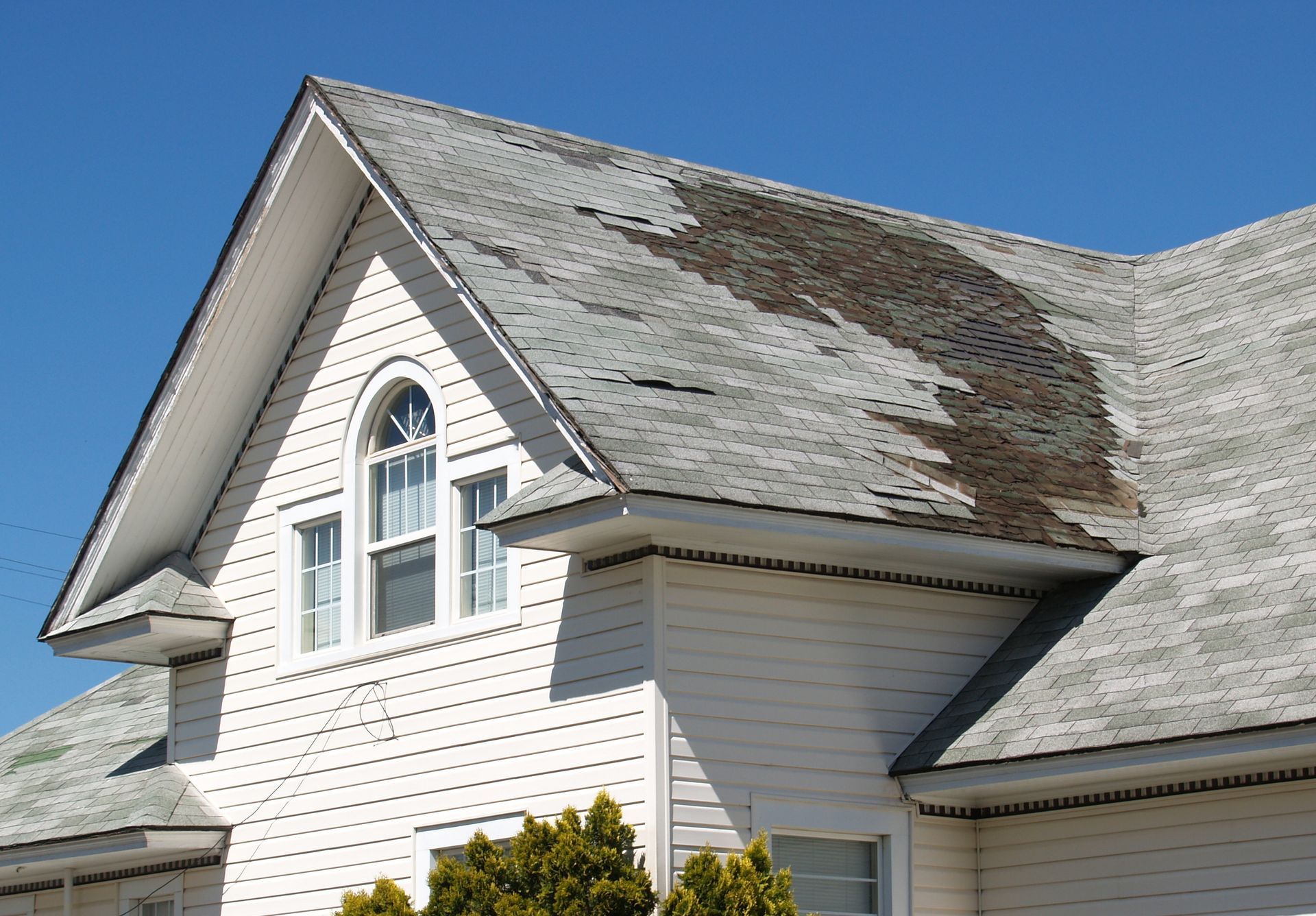 A white house with a roof that is missing shingles