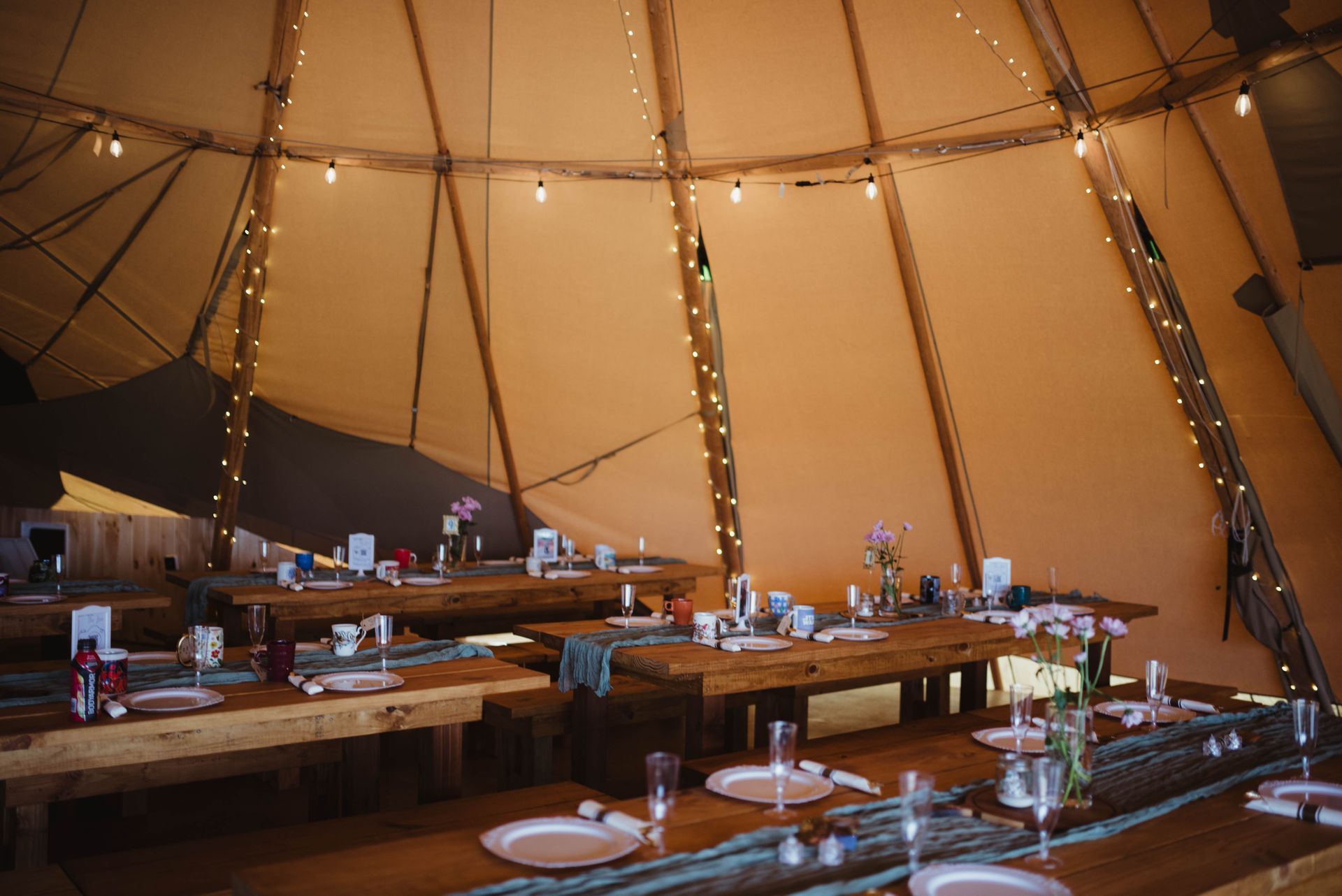 A large tent with tables and benches set up for a wedding reception.