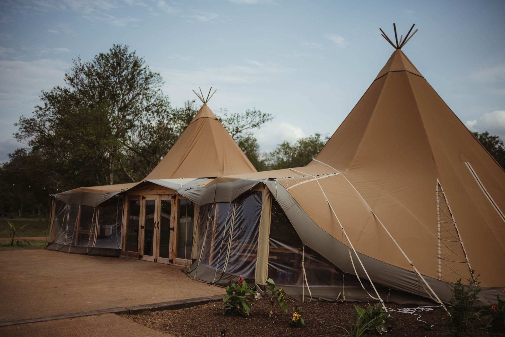 Two teepees are sitting next to each other in a field.
