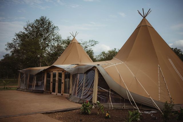 Two teepees are sitting next to each other in a field.