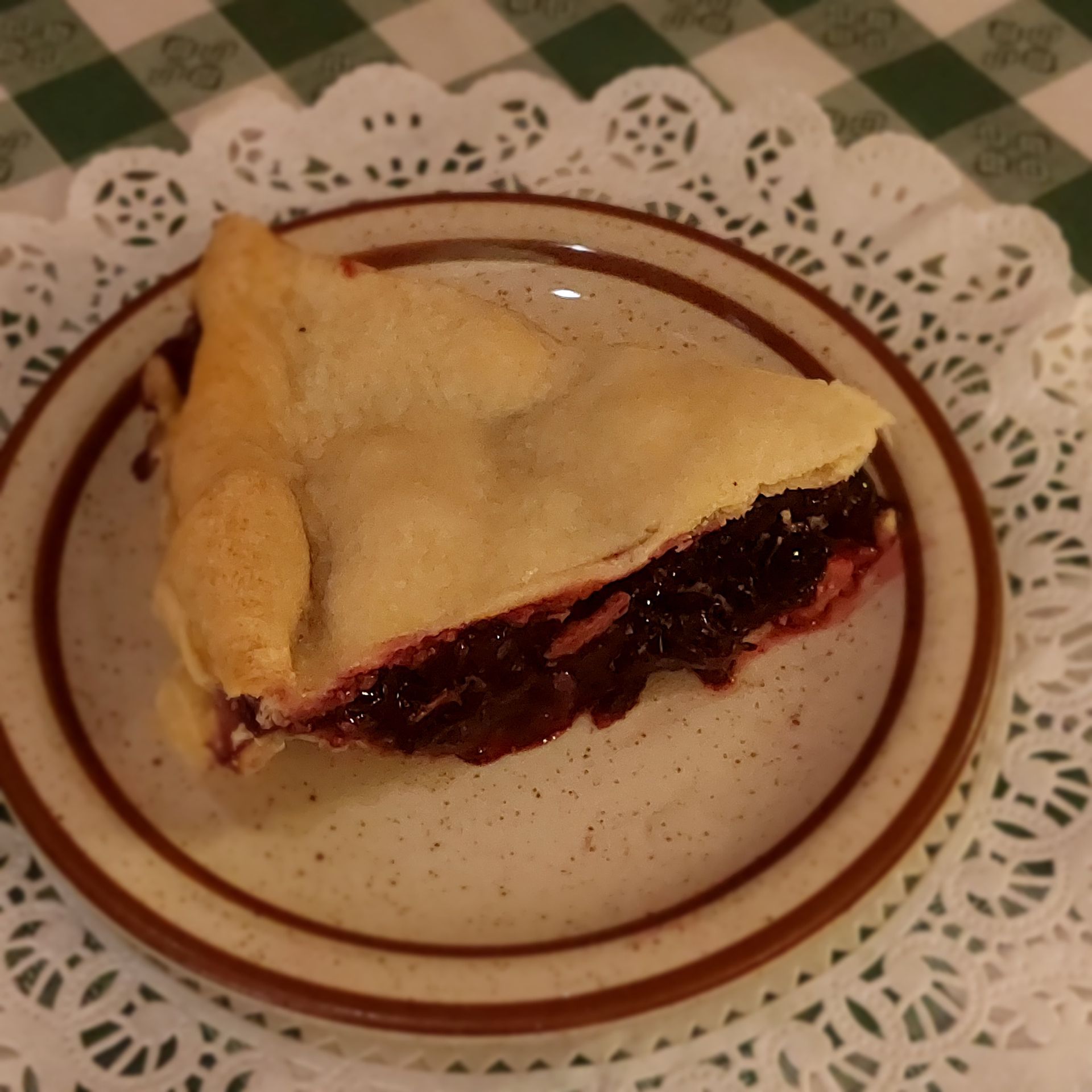 A slice of cherry pie on a plate on a table