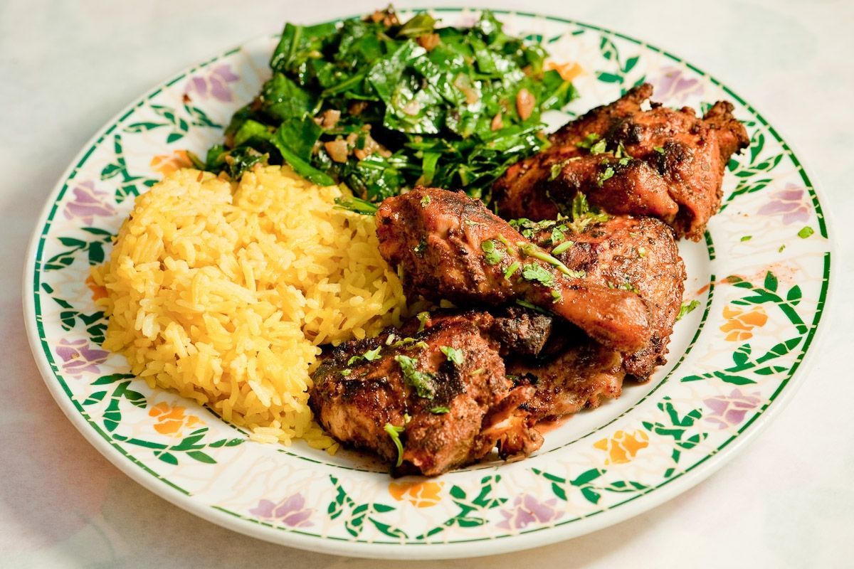 A plate of food with chicken , rice and spinach on a table.