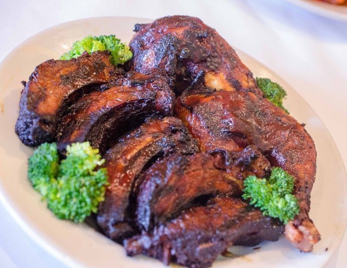 A white plate topped with ribs and broccoli on a table.