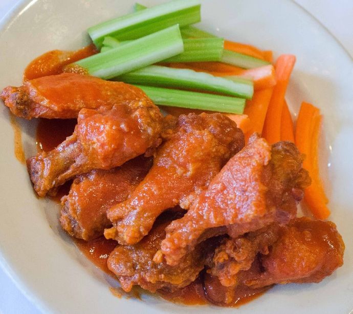 A white plate topped with chicken wings and celery sticks.