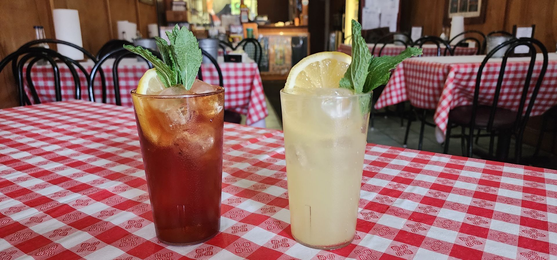 Two drinks are sitting on a checkered tablecloth on a table.