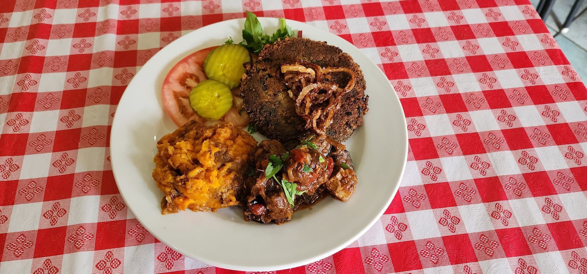 A plate of food on a checkered tablecloth on a table.