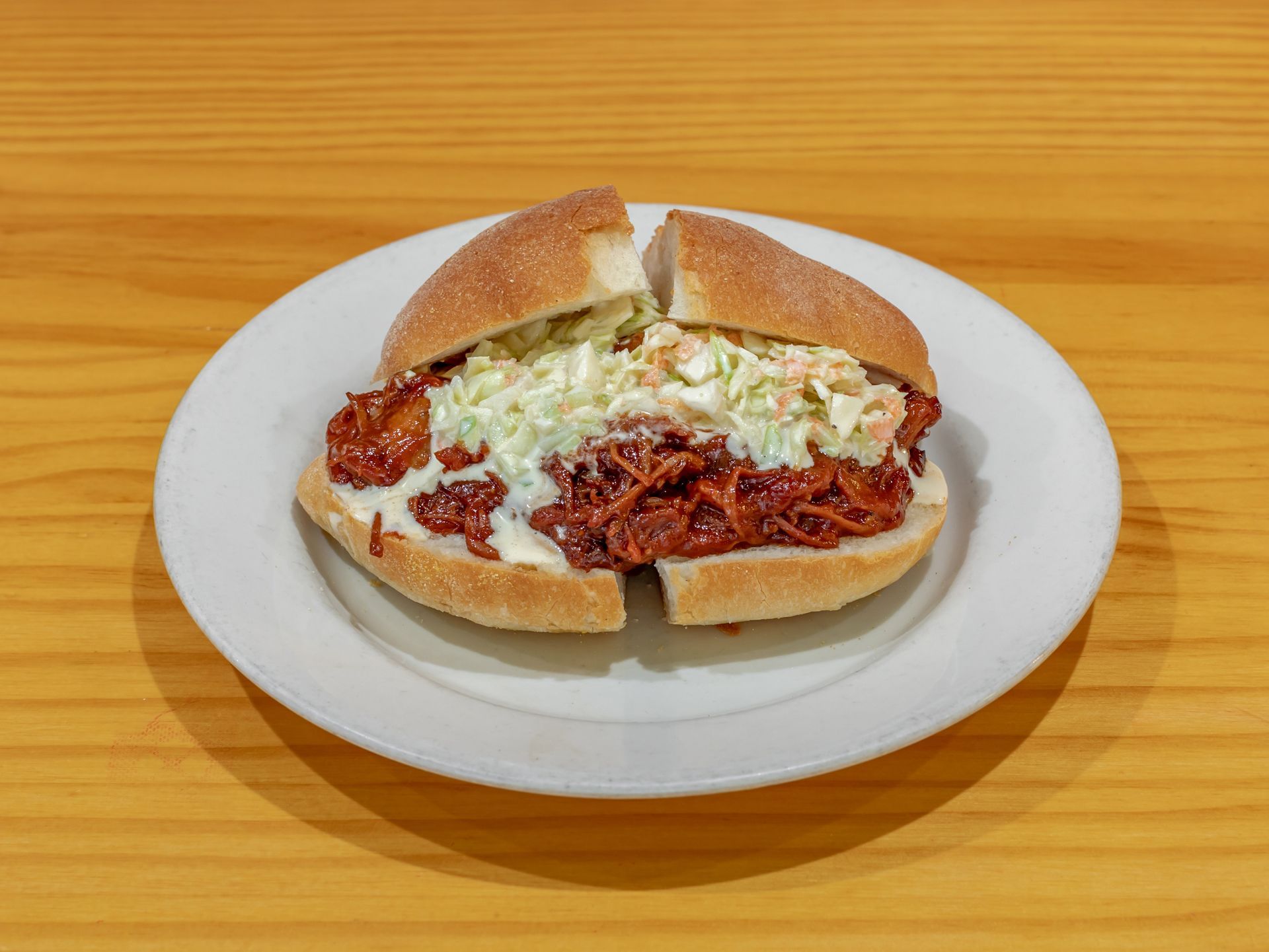 A pulled pork sandwich with coleslaw on a white plate