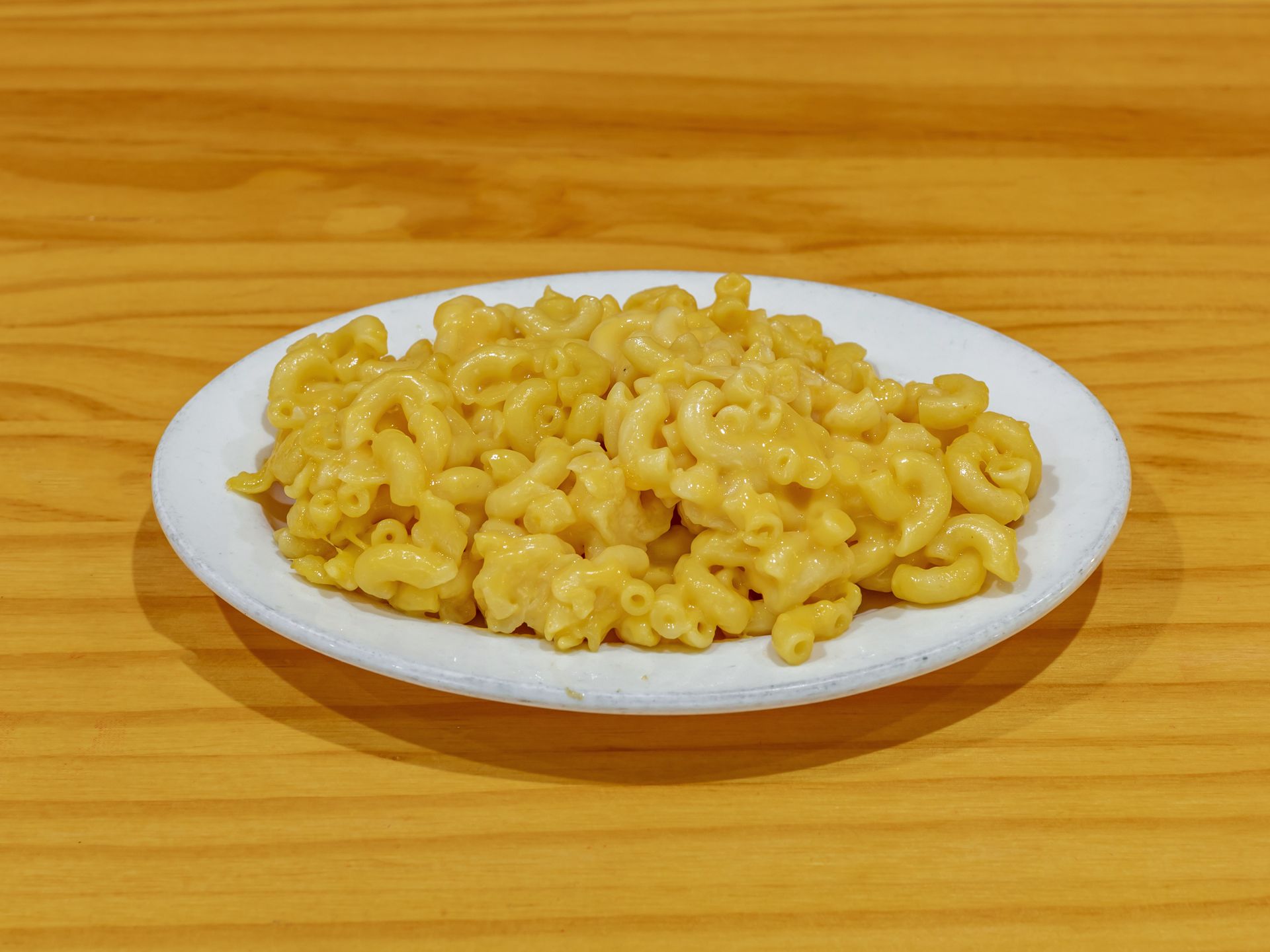 A white plate topped with macaroni and cheese on a wooden table.