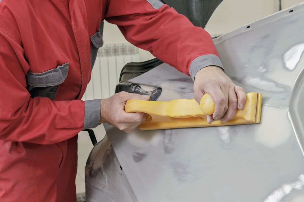 Person in Red Overalls Sanding a Car Door — Bowen Automotive in Bowen, QLD