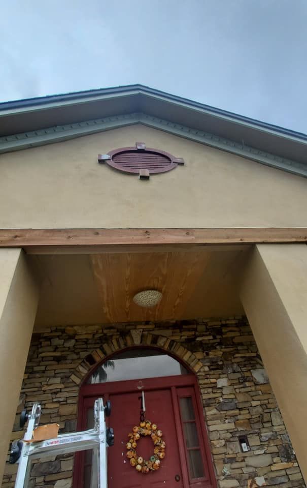 Front exterior view of a home entrance with a stone-accented doorway, a red front door, and a decorative oval plaque.