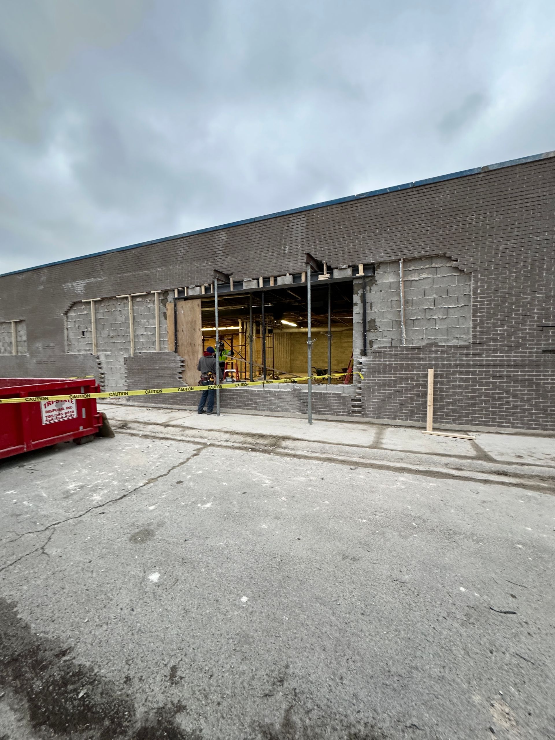 A red dumpster is parked in front of a building under construction.