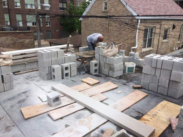A man is working on a brick wall in front of a house